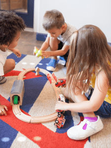 three kids playing together with a train set