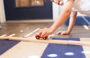 A child playing with a car on a wooden track