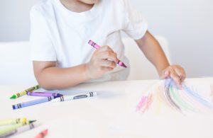 a kiddo coloring with crayons