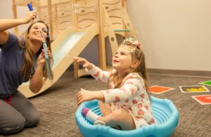 a staff member and a young girl playing with bubbles