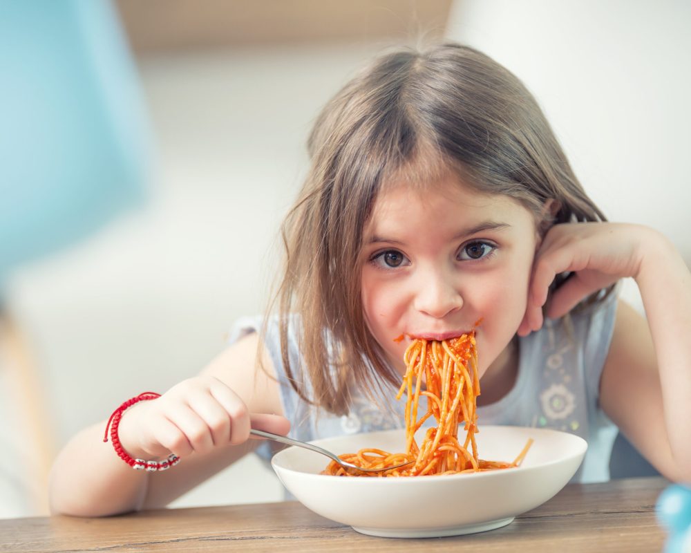 Cute little kid girl eating spaghetti bolognese at home. Cute little kid girl eating spaghetti bolognese at home.